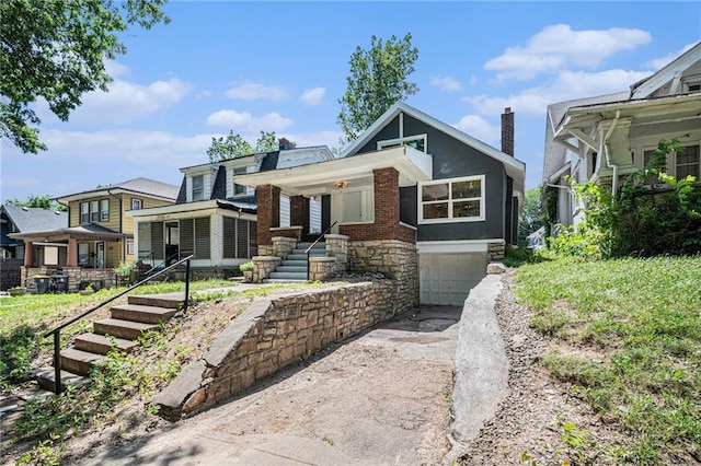 4036 Benton Blvd, Kansas City, MO 64130 - view of front of house with driveway, a garage, a chimney, a porch, and stone siding