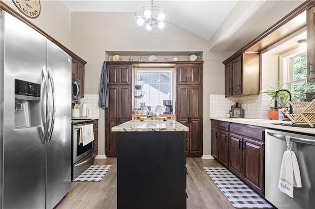 109 NW Whitlock Dr, Lees Summit, MO 64081 - kitchen featuring stainless steel appliances, vaulted ceiling, a kitchen island, tasteful backsplash, and light wood-style floors