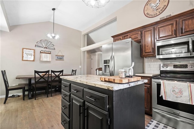 109 NW Whitlock Dr, Lees Summit, MO 64081 - kitchen with appliances with stainless steel finishes, lofted ceiling, backsplash, a kitchen island, and light wood-type flooring