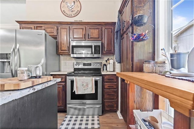 109 NW Whitlock Dr, Lees Summit, MO 64081 - kitchen featuring appliances with stainless steel finishes, light countertops, light wood finished floors, and decorative backsplash