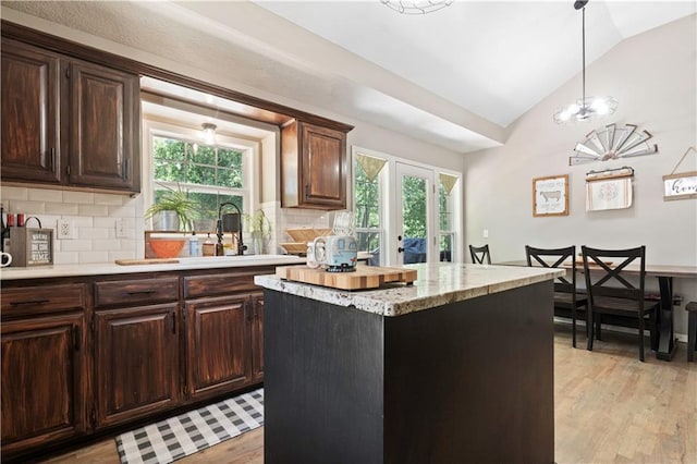 109 NW Whitlock Dr, Lees Summit, MO 64081 - kitchen featuring light wood-style floors, decorative backsplash, lofted ceiling, plenty of natural light, and dark brown cabinetry