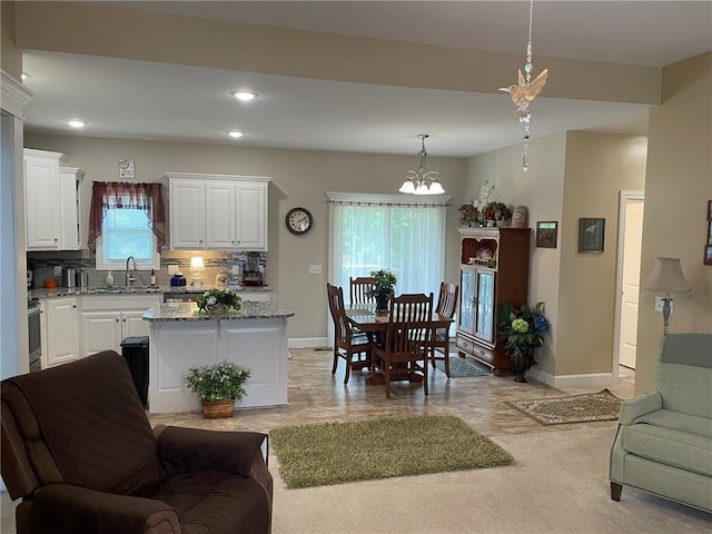 5205 University Ave, Saint Joseph, MO 64503 - kitchen featuring white cabinets, a chandelier, light stone countertops, decorative backsplash, and pendant lighting