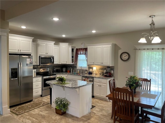5205 University Ave, Saint Joseph, MO 64503 - kitchen with stainless steel appliances, decorative backsplash, white cabinets, a center island, and light stone countertops