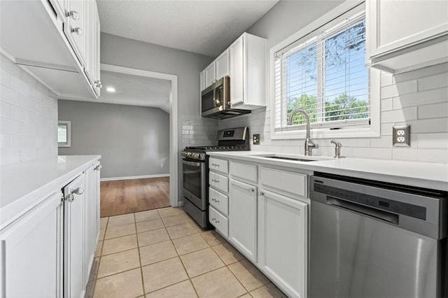 7617 W 63rd Ter, Overland Park, KS 66202 - kitchen with stainless steel appliances, tasteful backsplash, white cabinets, light countertops, and light tile patterned floors