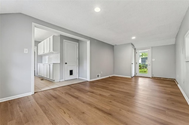 7617 W 63rd Ter, Overland Park, KS 66202 - spare room with light wood-style floors, recessed lighting, a textured ceiling, lofted ceiling, and a fireplace