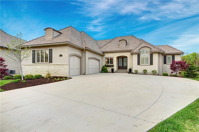 2144 W 89th Ter, Leawood, KS 66206 - view of front of house featuring an attached garage, stone siding, concrete driveway, stucco siding, and french doors