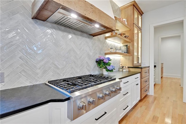 2144 W 89th Ter, Leawood, KS 66206 - kitchen with stainless steel gas cooktop, wall chimney range hood, dark countertops, decorative backsplash, and glass insert cabinets