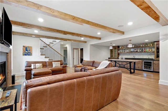 2144 W 89th Ter, Leawood, KS 66206 - living area with wine cooler, bar area, a glass covered fireplace, light wood-style floors, and beamed ceiling