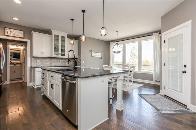 25096 W 87th St, Lenexa, KS 66227 - kitchen featuring stainless steel dishwasher, glass insert cabinets, a kitchen island with sink, a kitchen bar, and backsplash