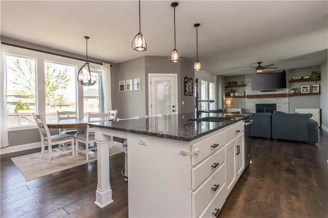 25096 W 87th St, Lenexa, KS 66227 - kitchen featuring a fireplace, a ceiling fan, dark wood-type flooring, dark stone countertops, and white cabinetry