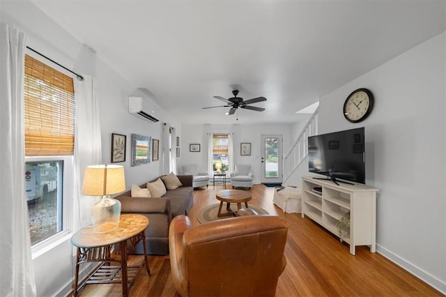 2017 W 48th St, Westwood, KS 66205 - living room featuring an AC wall unit, wood finished floors, ceiling fan, and stairway