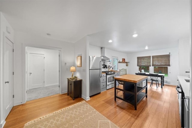 2017 W 48th St, Westwood, KS 66205 - kitchen with appliances with stainless steel finishes, wall chimney exhaust hood, light wood-style floors, recessed lighting, and light countertops
