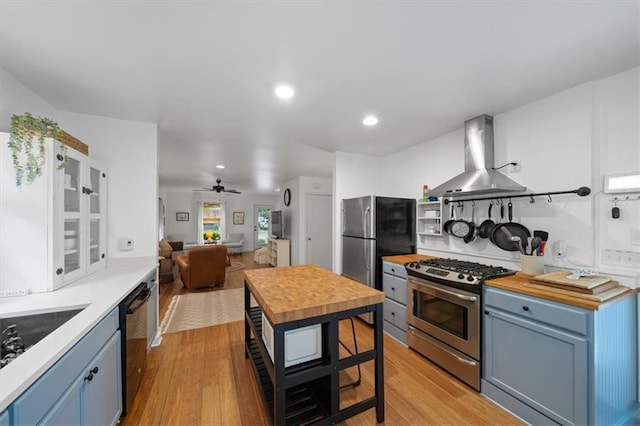 2017 W 48th St, Westwood, KS 66205 - kitchen with appliances with stainless steel finishes, wall chimney range hood, blue cabinetry, butcher block countertops, and recessed lighting