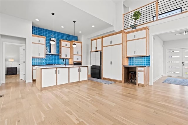 22615 W 87th Ter, Lenexa, KS 66227 - kitchen featuring freestanding refrigerator, decorative backsplash, white cabinets, light wood-type flooring, and hanging light fixtures