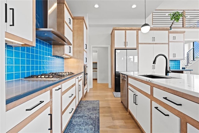 22615 W 87th Ter, Lenexa, KS 66227 - kitchen with wall chimney range hood, appliances with stainless steel finishes, pendant lighting, light wood-style floors, and white cabinetry