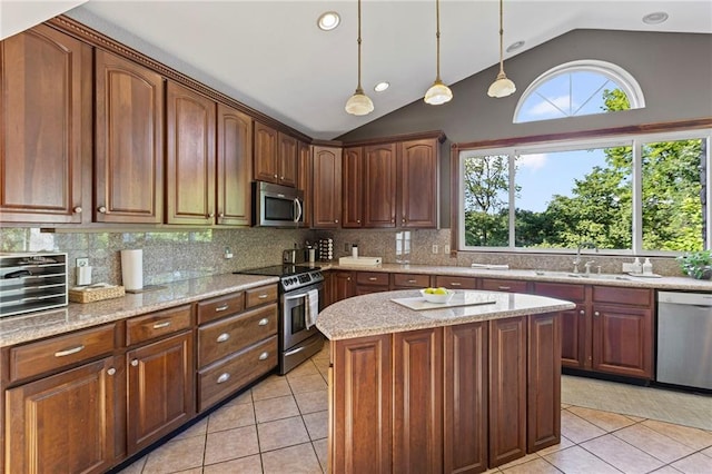 1015 S Wyckford Rd, Olathe, KS 66061 - kitchen with appliances with stainless steel finishes, vaulted ceiling, light tile patterned floors, a kitchen island, and pendant lighting