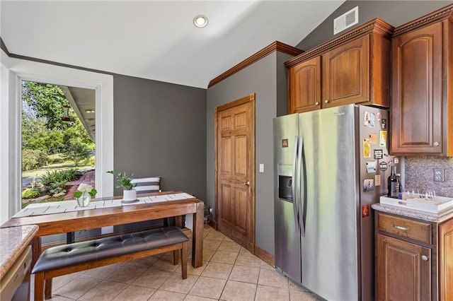 1015 S Wyckford Rd, Olathe, KS 66061 - kitchen with stainless steel fridge, light tile patterned floors, tasteful backsplash, light countertops, and brown cabinetry