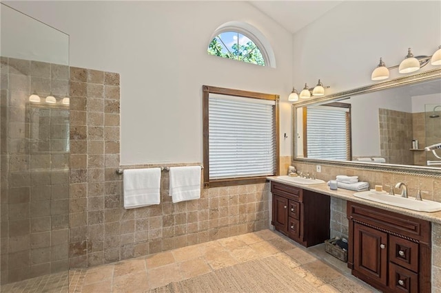 1015 S Wyckford Rd, Olathe, KS 66061 - bathroom with tile walls, a walk in shower, double vanity, a wainscoted wall, and high vaulted ceiling