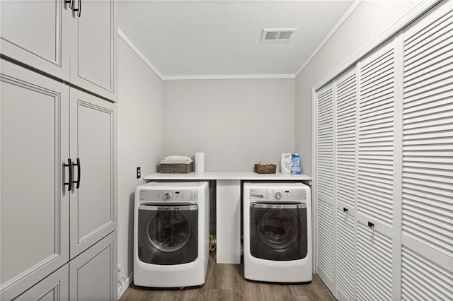 1015 S Wyckford Rd, Olathe, KS 66061 - laundry area featuring washer and dryer, cabinet space, ornamental molding, wood finished floors, and a textured ceiling