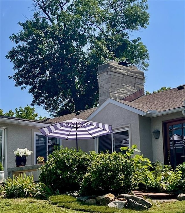 1015 S Wyckford Rd, Olathe, KS 66061 - view of side of property with stucco siding, a chimney, and roof with shingles