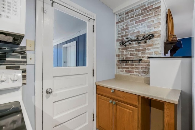 1202 S Willow St, Ottawa, KS 66067 - kitchen featuring light countertops, brown cabinets, and brick wall