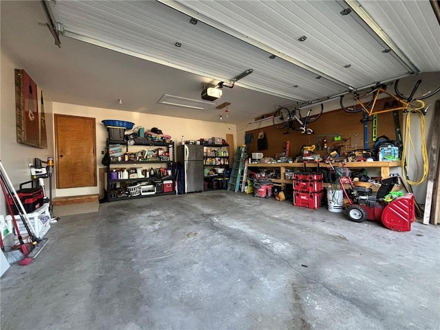 2006 Buckingham St, Saint Joseph, MO 64506 - garage featuring a garage door opener, freestanding refrigerator, and a workshop area