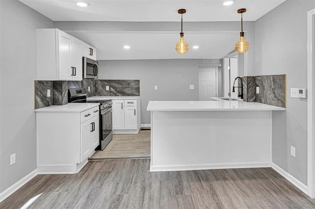 804 S Cedar Ave, Independence, MO 64053 - kitchen with appliances with stainless steel finishes, a peninsula, light wood-style floors, backsplash, and white cabinetry