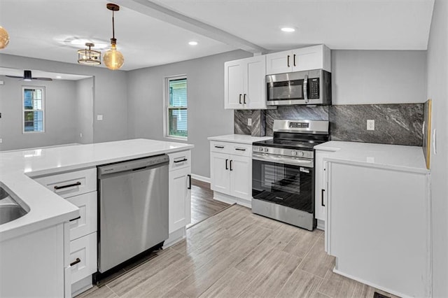 804 S Cedar Ave, Independence, MO 64053 - kitchen with appliances with stainless steel finishes, white cabinets, recessed lighting, decorative light fixtures, and tasteful backsplash