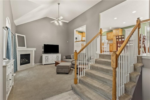 2105 NW Sweetgum Ct, Grain Valley, MO 64029 - living room featuring a ceiling fan, a fireplace, stairway, light carpet, and lofted ceiling