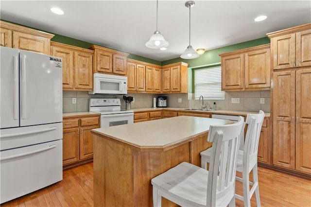 2105 NW Sweetgum Ct, Grain Valley, MO 64029 - kitchen with white appliances, light wood-style floors, light countertops, backsplash, and recessed lighting