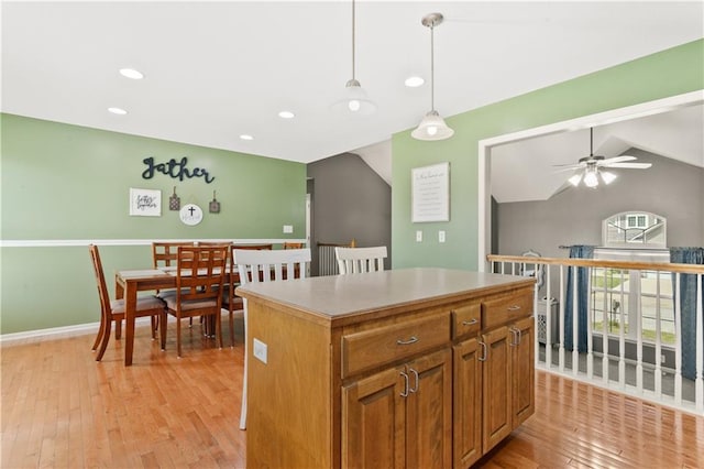 2105 NW Sweetgum Ct, Grain Valley, MO 64029 - kitchen featuring a kitchen island, light wood finished floors, a ceiling fan, pendant lighting, and brown cabinets