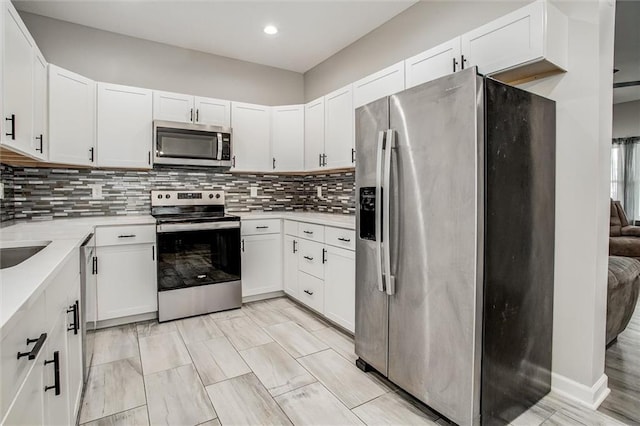 311 S 3rd St, Odessa, MO 64076 - kitchen featuring appliances with stainless steel finishes, light countertops, tasteful backsplash, white cabinets, and recessed lighting