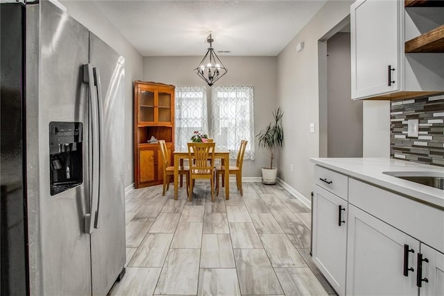 311 S 3rd St, Odessa, MO 64076 - kitchen with stainless steel fridge, open shelves, a chandelier, light countertops, and white cabinets