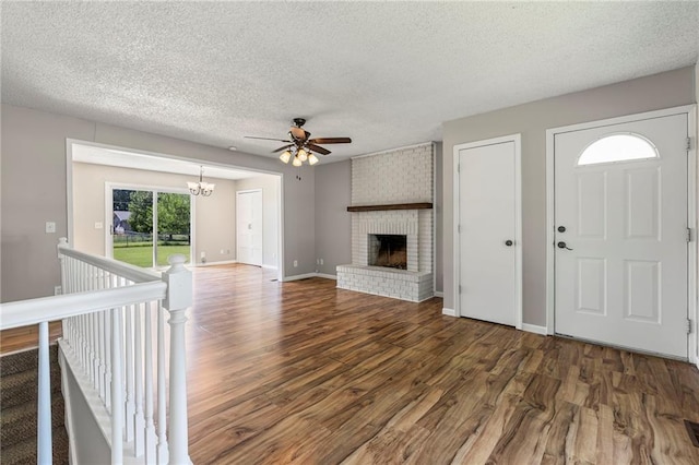 1138 S Willow St, Ottawa, KS 66067 - unfurnished living room with wood finished floors, ceiling fan, a textured ceiling, a chandelier, and a brick fireplace