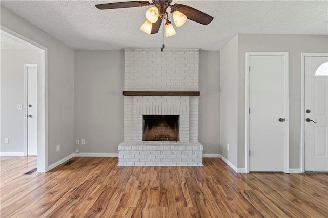 1138 S Willow St, Ottawa, KS 66067 - unfurnished living room with ceiling fan, wood finished floors, a textured ceiling, and a brick fireplace
