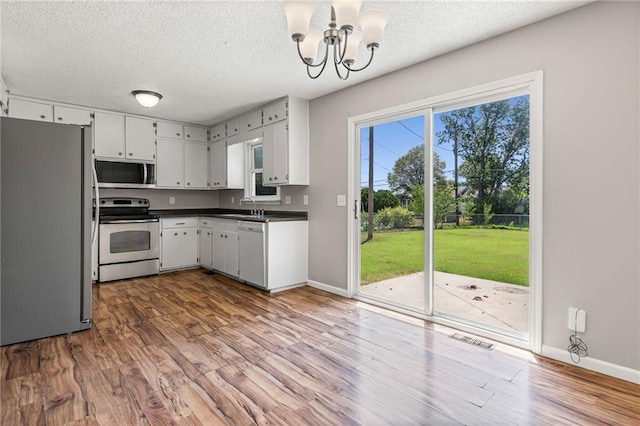 1138 S Willow St, Ottawa, KS 66067 - kitchen featuring stainless steel appliances, a chandelier, wood finished floors, a textured ceiling, and dark countertops