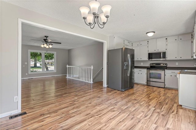 1138 S Willow St, Ottawa, KS 66067 - kitchen with appliances with stainless steel finishes, dark countertops, light wood-style floors, a chandelier, and a textured ceiling
