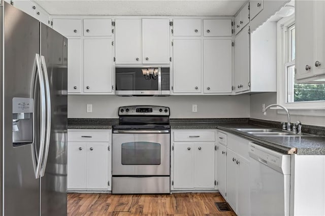 1138 S Willow St, Ottawa, KS 66067 - kitchen with stainless steel appliances, dark countertops, white cabinetry, and wood finished floors