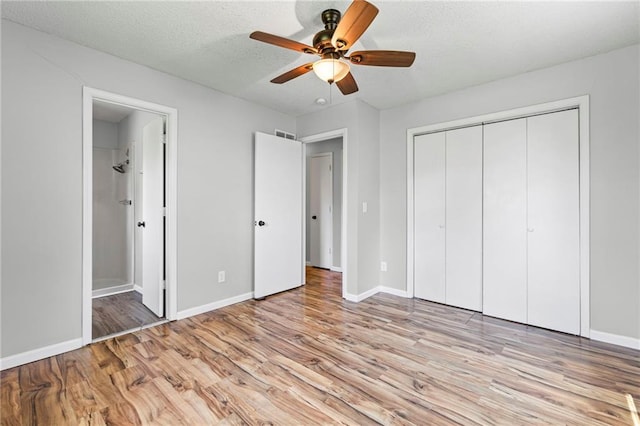 1138 S Willow St, Ottawa, KS 66067 - unfurnished bedroom featuring wood finished floors, ensuite bathroom, a closet, ceiling fan, and a textured ceiling
