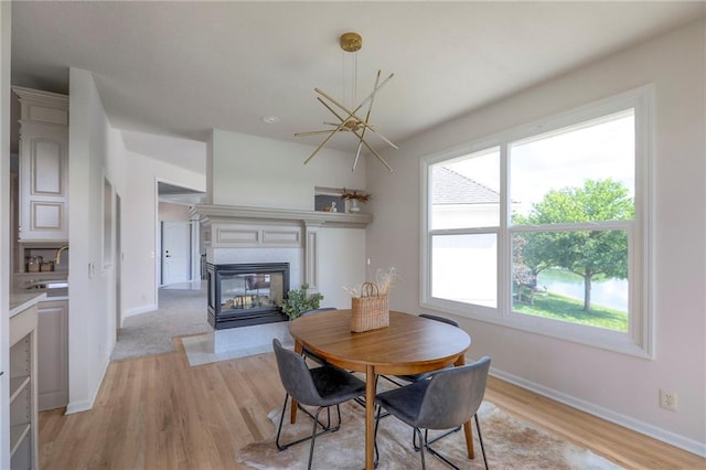 129 SE Chelsea Dr, Lees Summit, MO 64063 - dining space featuring light wood-type flooring, a chandelier, and a multi sided fireplace