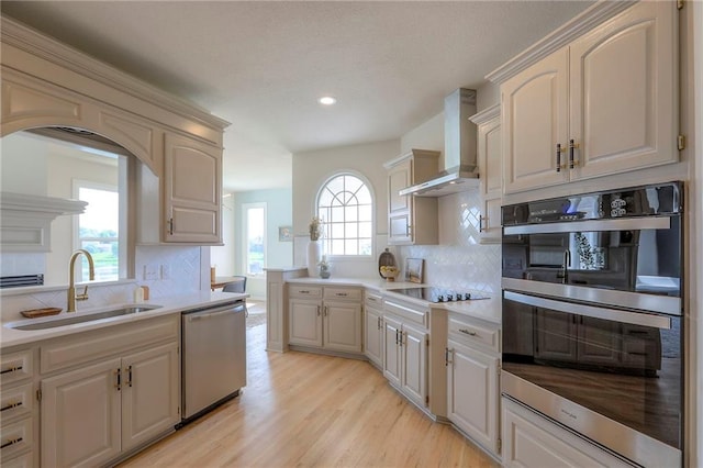 129 SE Chelsea Dr, Lees Summit, MO 64063 - kitchen with stainless steel appliances, wall chimney range hood, light countertops, light wood-style floors, and recessed lighting