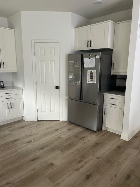 211 Harrison St, Pomona, KS 66076 - kitchen with freestanding refrigerator, white cabinets, light wood finished floors, and light countertops