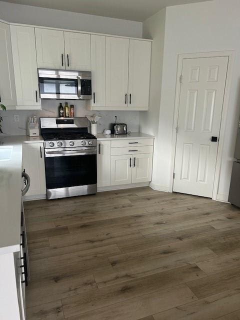 211 Harrison St, Pomona, KS 66076 - kitchen with stainless steel appliances, white cabinetry, wood finished floors, and light countertops