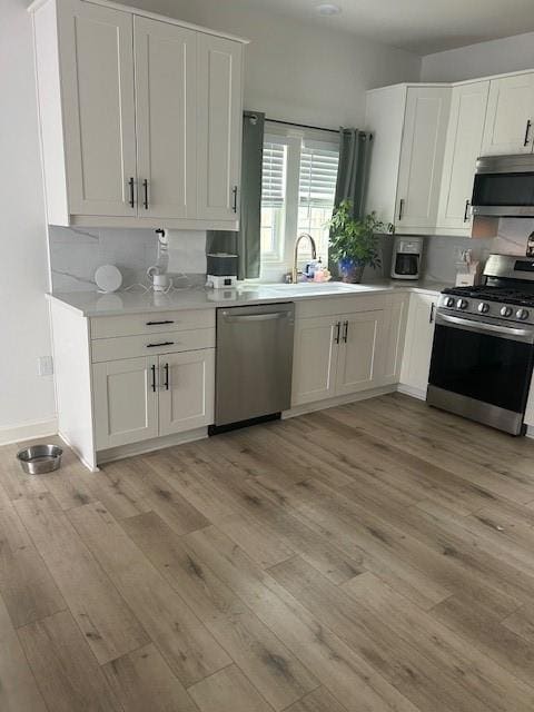 211 Harrison St, Pomona, KS 66076 - kitchen with stainless steel appliances, light countertops, light wood-type flooring, and white cabinets