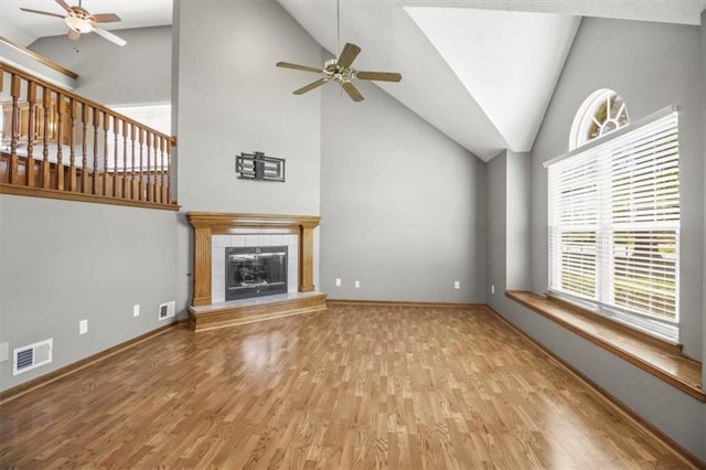 3605 NW Pier Ct, Blue Springs, MO 64015 - unfurnished living room featuring a ceiling fan, wood finished floors, a tiled fireplace, and high vaulted ceiling