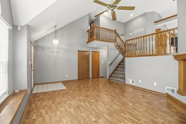 3605 NW Pier Ct, Blue Springs, MO 64015 - unfurnished living room with wood finished floors, a ceiling fan, healthy amount of natural light, high vaulted ceiling, and stairway
