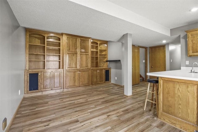 3605 NW Pier Ct, Blue Springs, MO 64015 - kitchen with light wood-style flooring, a breakfast bar, light countertops, a textured ceiling, and brown cabinets