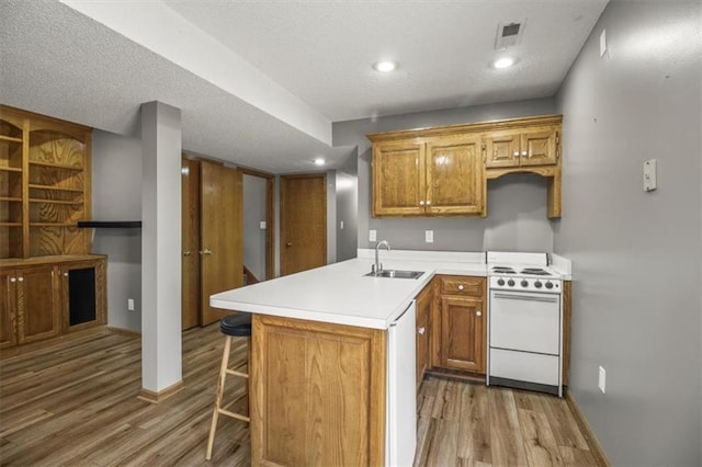 3605 NW Pier Ct, Blue Springs, MO 64015 - kitchen with white electric stove, light wood-style flooring, a peninsula, light countertops, and recessed lighting