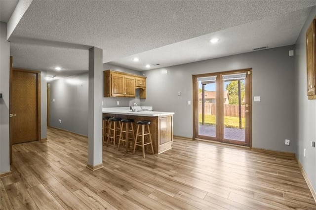 3605 NW Pier Ct, Blue Springs, MO 64015 - kitchen with a textured ceiling, a kitchen bar, light wood-style flooring, light countertops, and recessed lighting