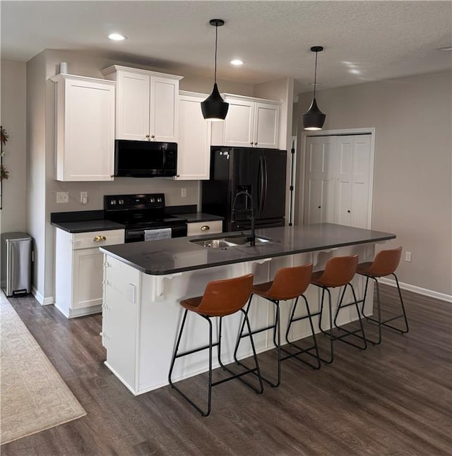 1141 S Main St, Ottawa, KS 66067 - kitchen featuring black appliances, dark countertops, dark wood finished floors, white cabinets, and recessed lighting